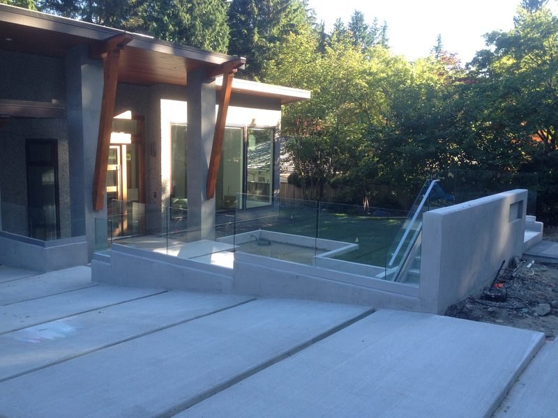 Glass railing around a concrete courtyard with a glass stair guard