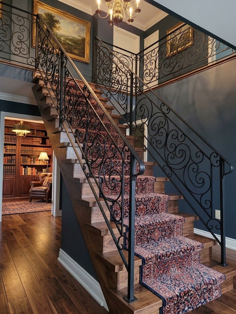Wrought iron interior stair railing with scrollwork panels and a matching landing guard