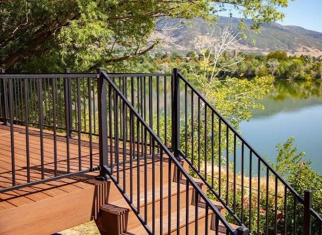 Black metal deck railing following a curved deck edge above a lake